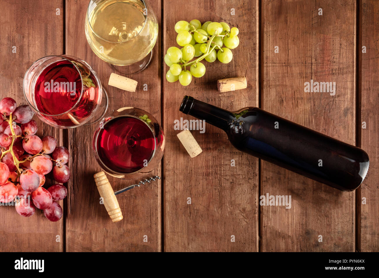Dégustation de vin dans une cave. Une photo de verres de rouge, rose, et le vin blanc avec une bouteille, des raisins et une corkscew vintage et bouchons, tourné par le haut sur un fond de bois rustique foncé with copy space Banque D'Images