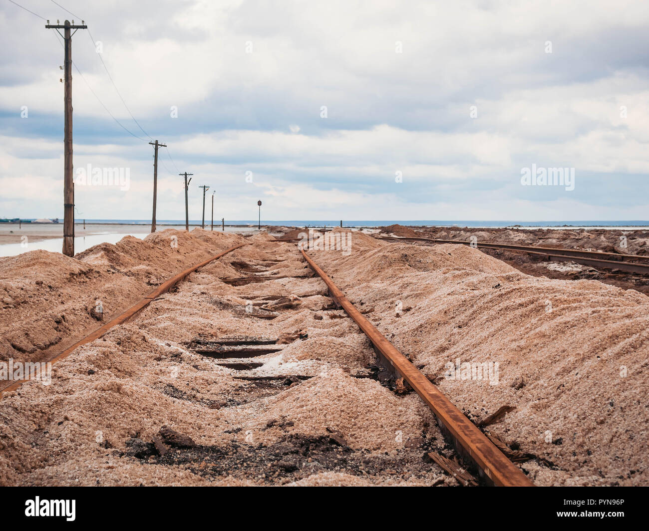 Rusty razy rails et traverses pourries couvertes de sel sur l'ancienne voie ferrée sur un monticule à l'extraction de sel lac près de saumure. Banque D'Images