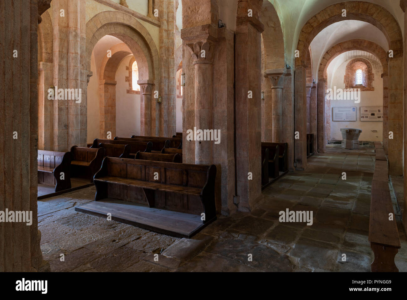 Gourdon, France - 3 août 2018 : Intérieur avec la couleur rose, des banquettes en bois et d'énormes piliers de l'église romane à Gourdon, Saône-et-Loire, France Banque D'Images
