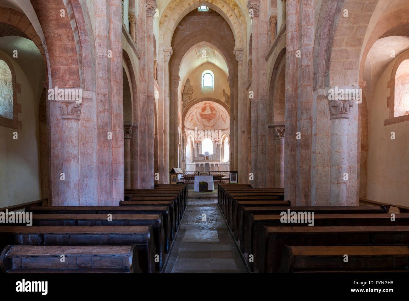 Gourdon, France - 3 août 2018 : Intérieur avec la couleur rose, des banquettes en bois et d'énormes piliers de l'église romane à Gourdon, Saône-et-Loire, France Banque D'Images