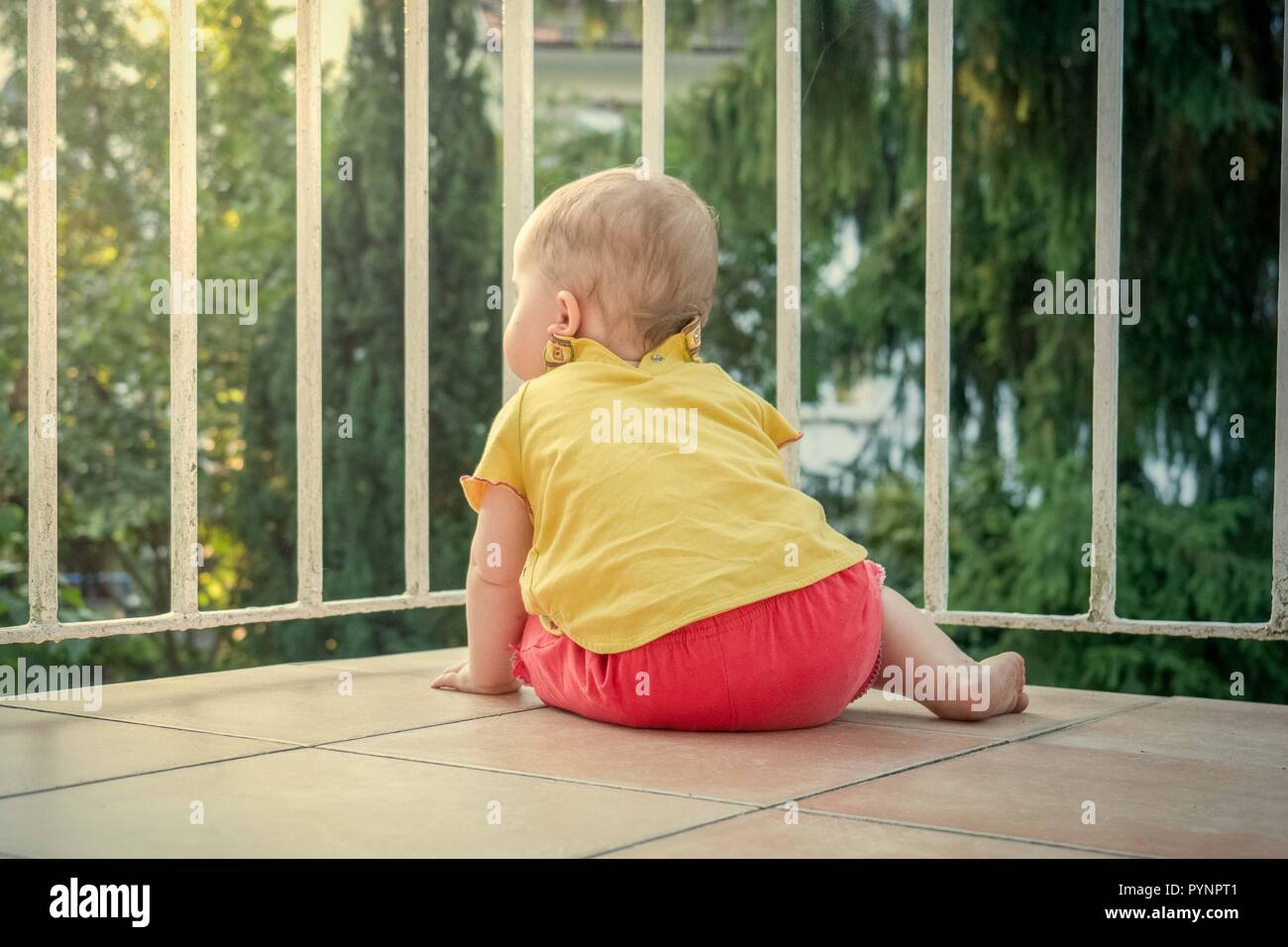 Petit bambin explore le nouveau monde à partir d'un balcon Banque D'Images