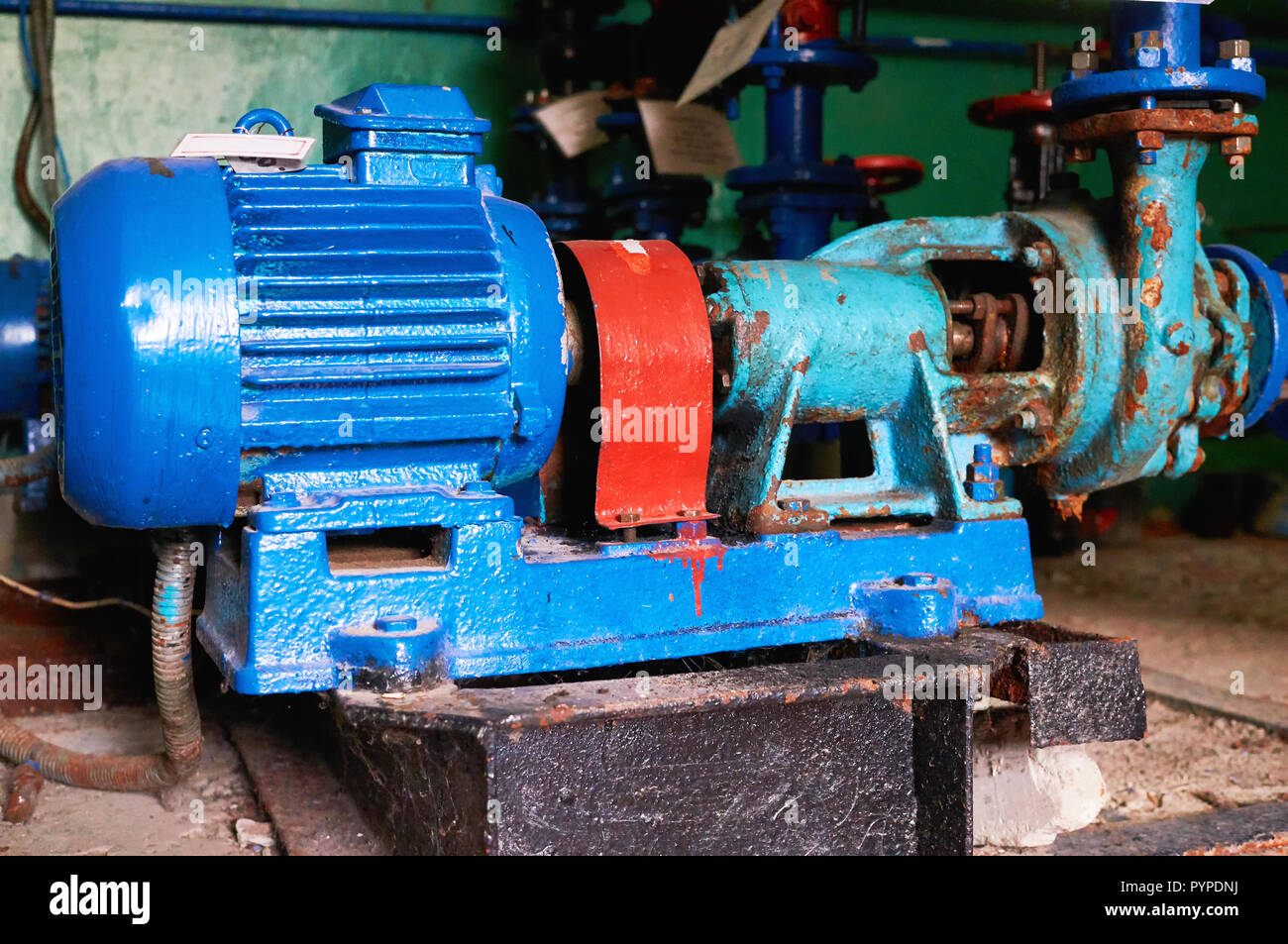 Vieux, rouillé rayures pompe à eau avec un moteur électrique teintée dans la couleur bleue sur le tuyau d'eau froide. Banque D'Images