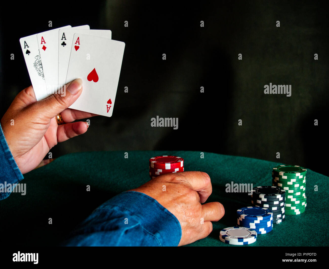 Une personne qui joue au poker avec les quatre as d'un jeu à la main et des  jetons de poker de différentes couleurs sur un tapis vert Photo Stock -  Alamy
