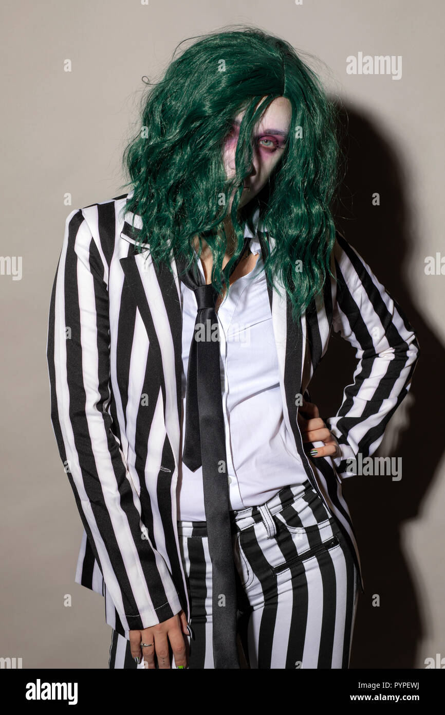 Une jeune femme s'habille pour l'Halloween dans un pinstripe costume et les cheveux verts. Banque D'Images