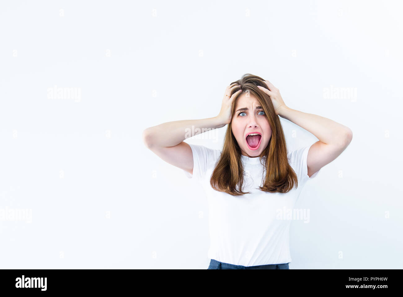 Horrible, stress, choc. Jeune femme regarde surpris émotionnelle, adhérents de l'appareil photo la tête dans les mains et ouvrant la bouche isolé sur fond blanc. Hu Banque D'Images