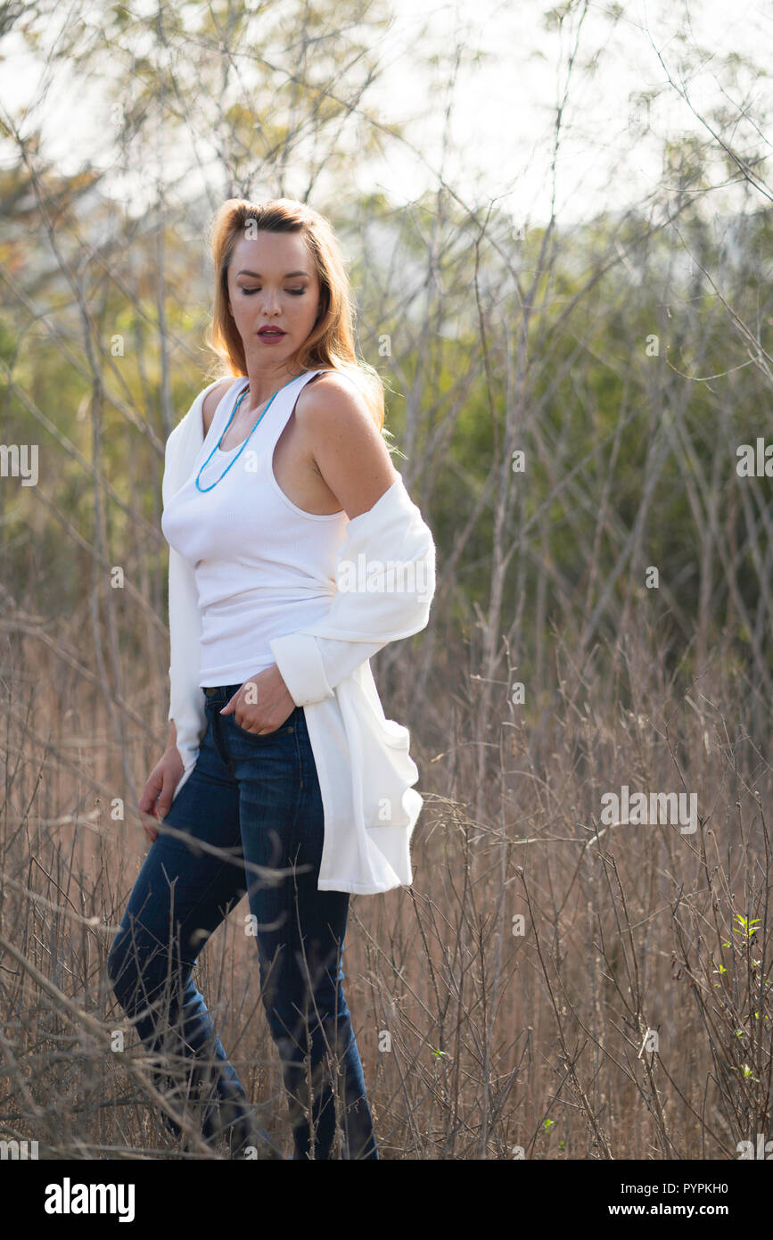 Une jeune femme pose dans le champ ouvert portant une chemise blanche et un  jean bleu Photo Stock - Alamy