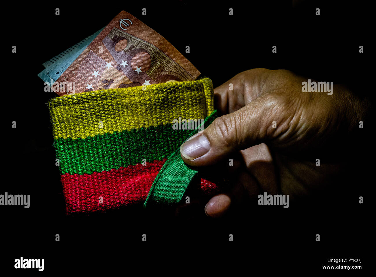 Portefeuille minimaliste avec des couleurs pan-africaine, ou les couleurs du drapeau national de la Lituanie, dans la main d'une personne. Billets à demi caché dans le portefeuille. Banque D'Images