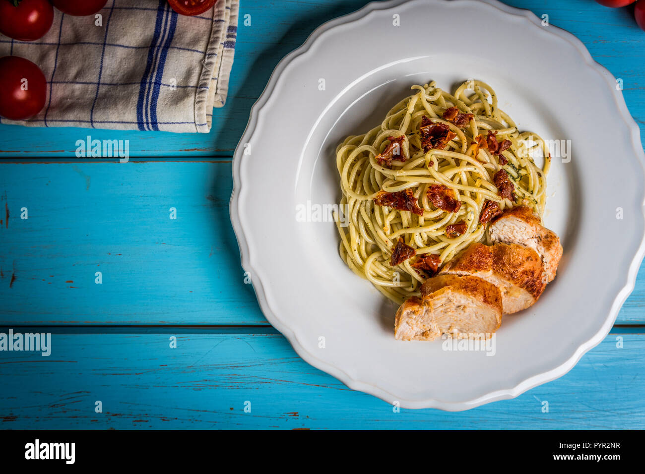 Spaghetti pâtes italiennes avec du poulet, tomates séchées et basilic Pesto sur tableau bleu Banque D'Images