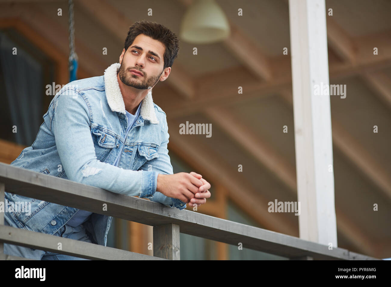 Jeune homme rêveur reposant sur balcon Banque D'Images