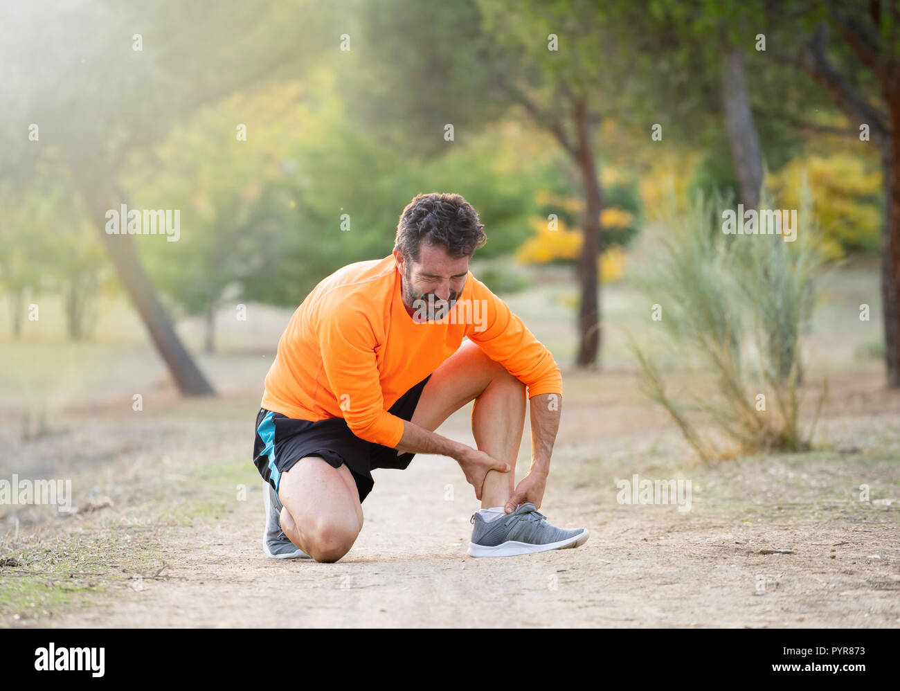 Athletic runner homme hurlant de douleur tenant sa cheville avec pied douloureux maux de jambe de s'exécuter et accident d'entraînement en plein air dans le parc en Physique Banque D'Images