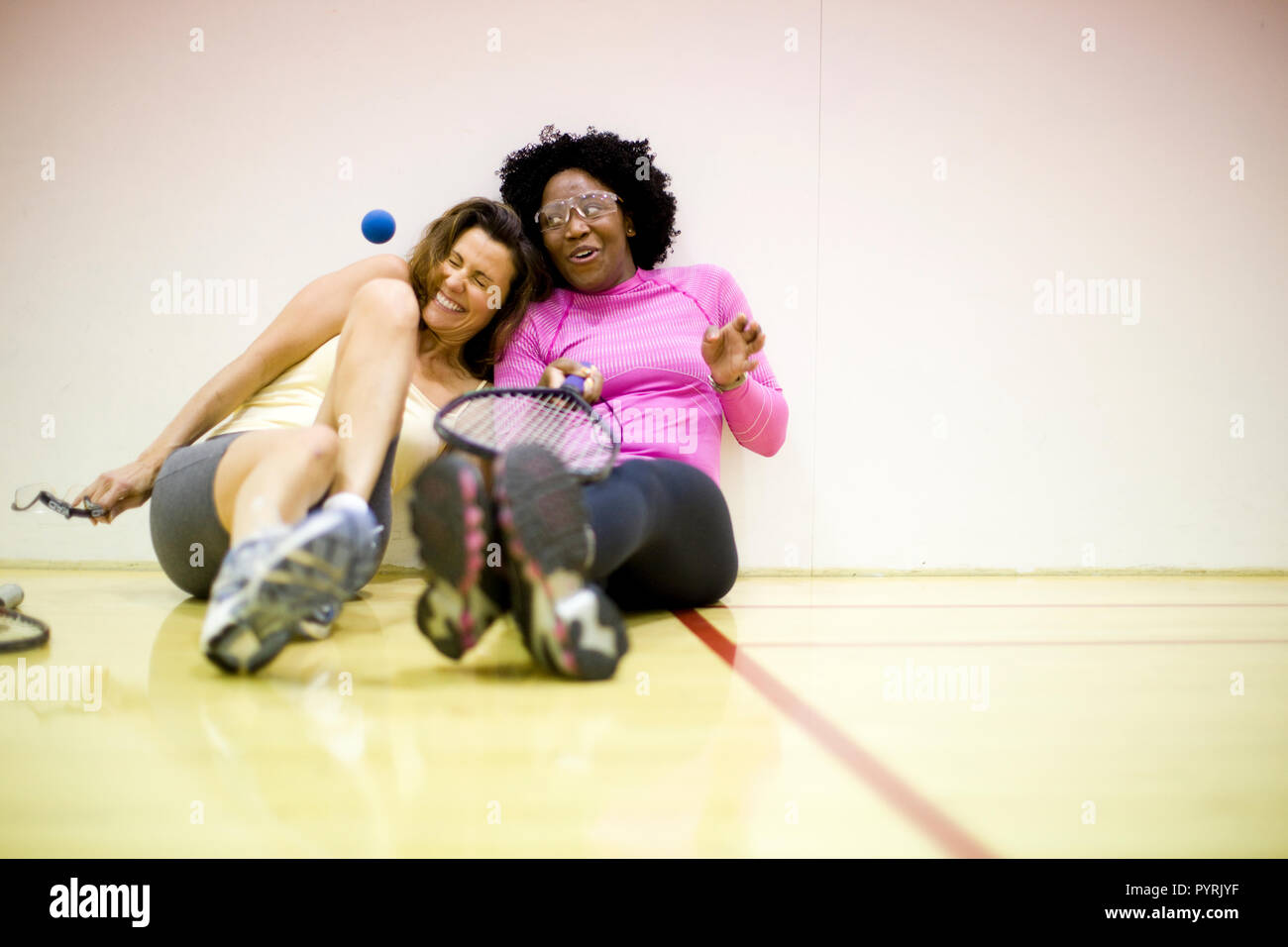 Deux femmes souriant assis ensemble sur un terrain de racquetball. Banque D'Images