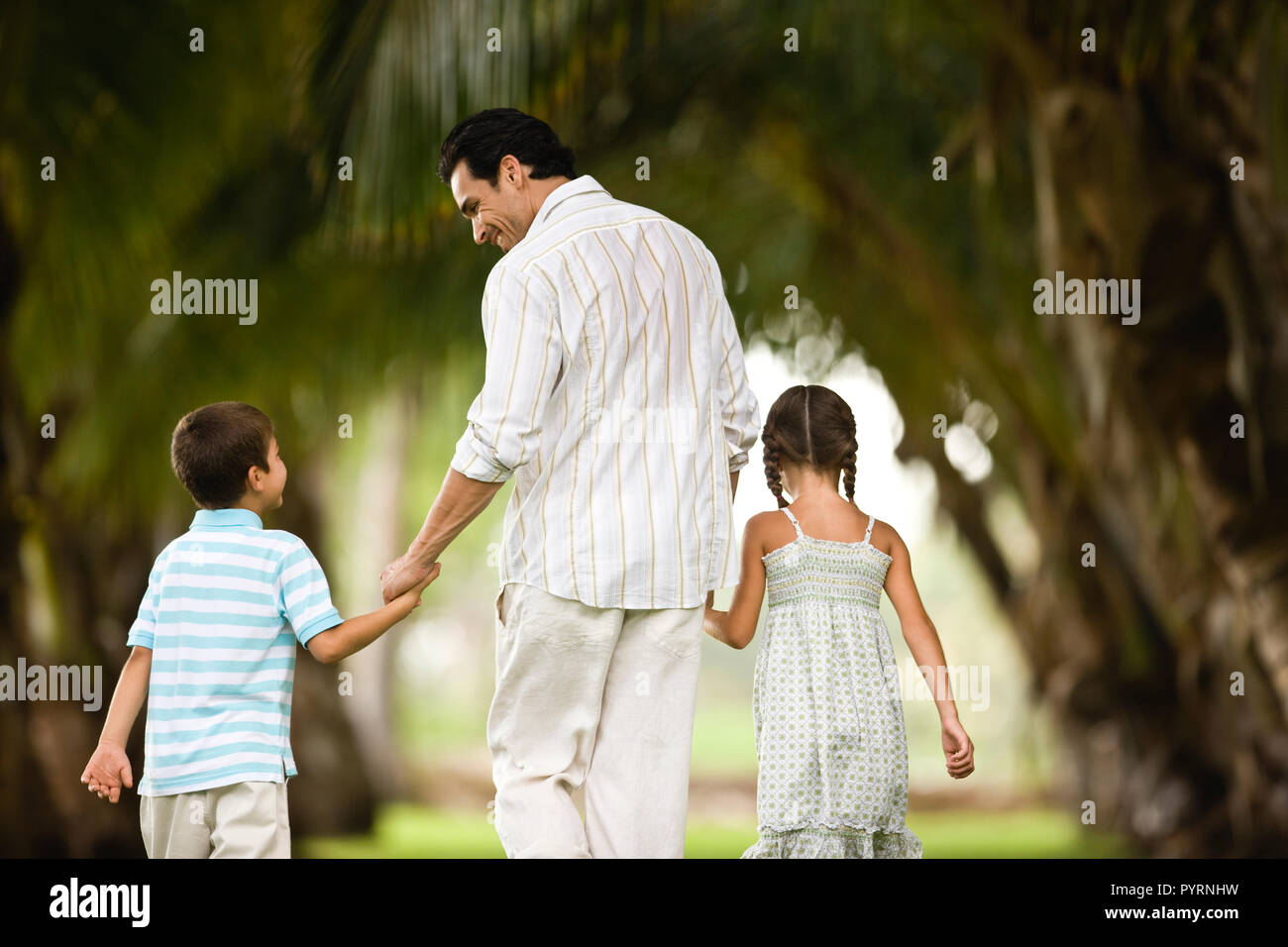 Vue arrière du père et des enfants marchant main dans la main. Banque D'Images