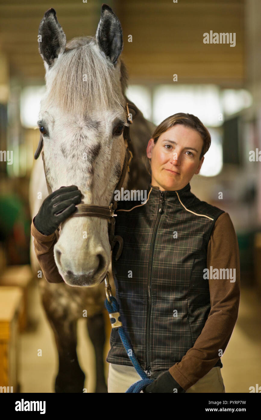 Portrait of a Mid adult woman et son cheval dans une étable. Banque D'Images