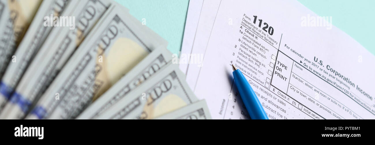 1120 formulaire d'impôt se trouve près de cent dollars et stylo bleu sur un fond bleu clair. Nous joindre - Déclaration de revenus des sociétés. Banque D'Images