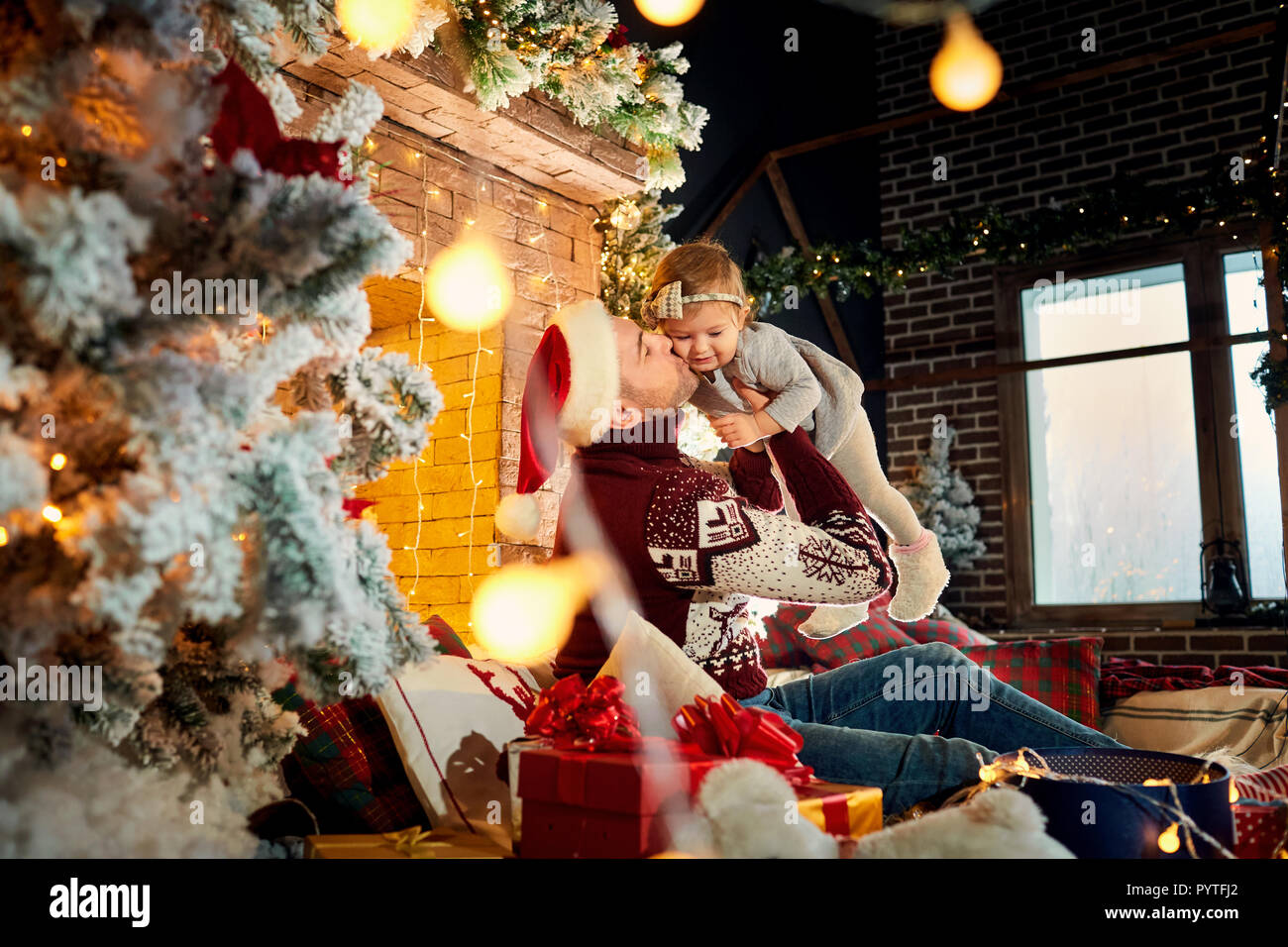 Père avec un bébé dans un Santa Claus hat dans une chambre de Noël le jour de Noël. Banque D'Images