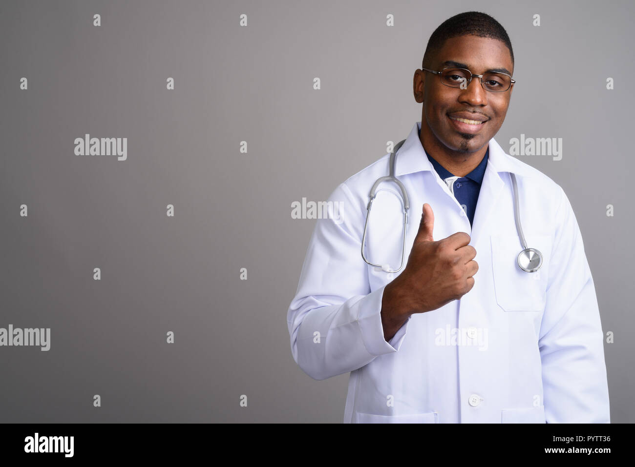 Beau jeune homme africain médecin contre l'arrière-plan gris Banque D'Images