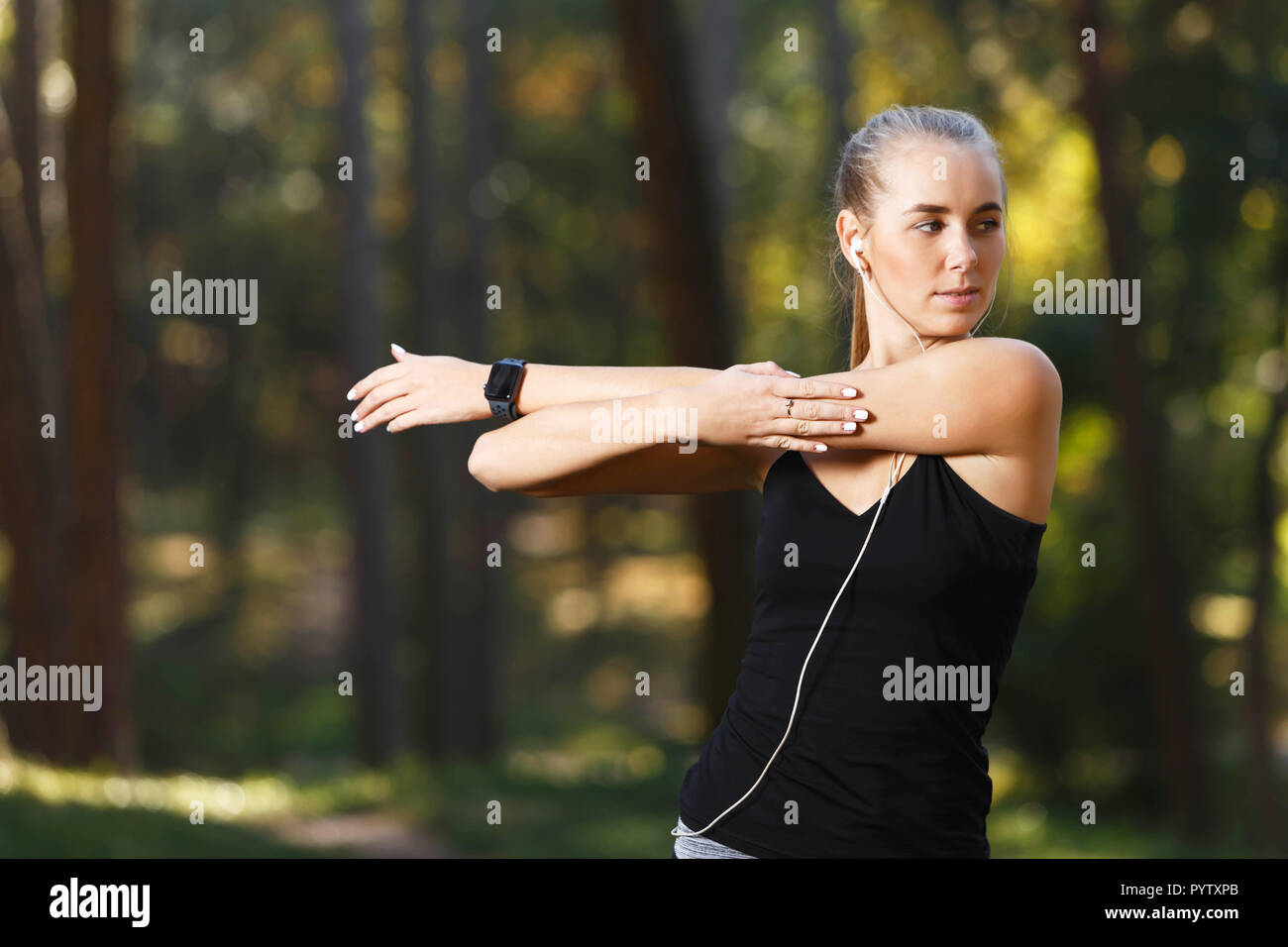 Portrait de jeune femme portant des vêtements de sport sportish étirement et l'écoute de la musique dans le parc ensoleillé, mode de vie sain et les gens concept Banque D'Images