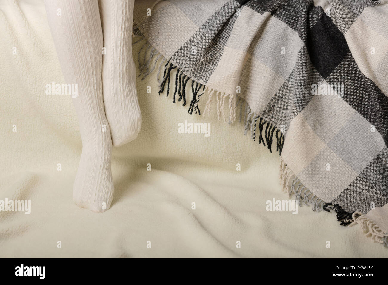 Les jambes des femmes en collant en tricot blanc chaud sur un fond blanc en fausse fourrure. Banque D'Images
