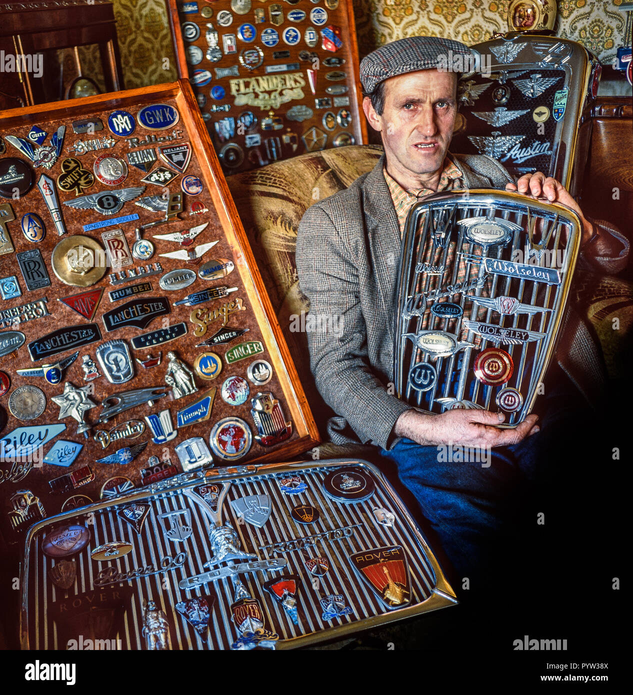 Brecon Beacons, Pays de Galles, Royaume-Uni, Novembre 2,1988 : Un agriculteur pose avec ses nombreuses collection d'insignes de voiture de son domicile. Tourné sur des films de format moyen. Banque D'Images