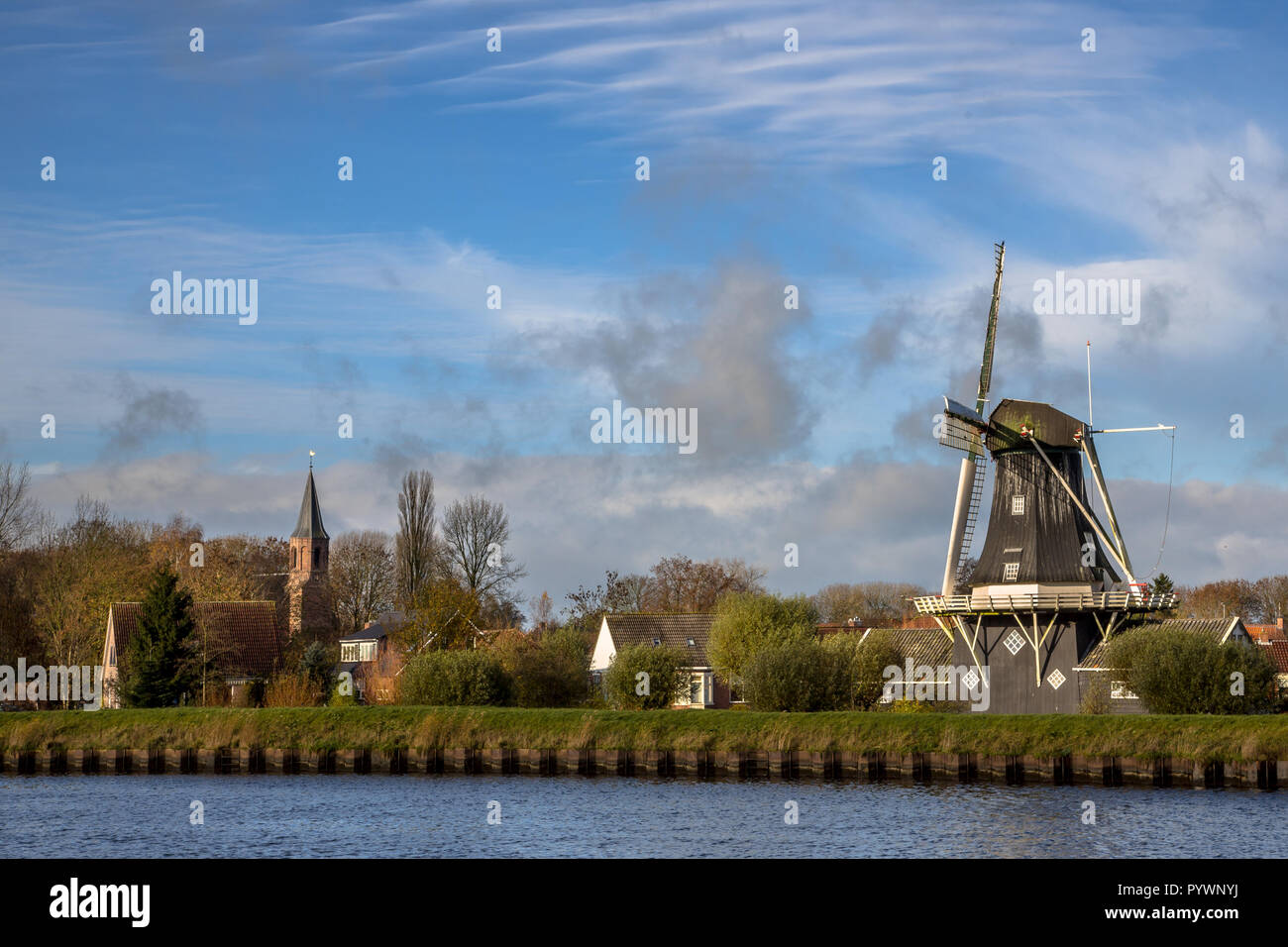 Voir l'historique du moulin à vent en bois et chirch dans le petit village de Woltersum à partir de l'eau dans la province de Groningue, Pays-Bas Banque D'Images