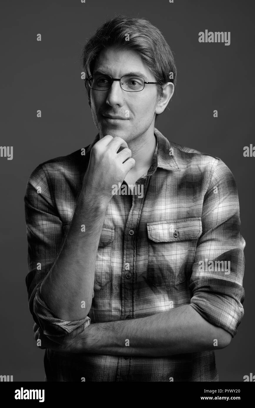Bel homme portant des lunettes contre l'arrière-plan gris en noir Banque D'Images