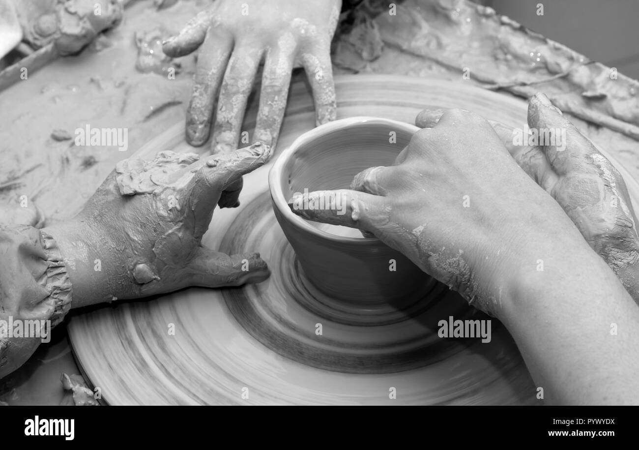 L'enseignant débutant et mains dans l'argile au processus de fabrication de vaisselle sur les poteries roue. Les potiers au travail. Image aux tons noir et blanc. Banque D'Images