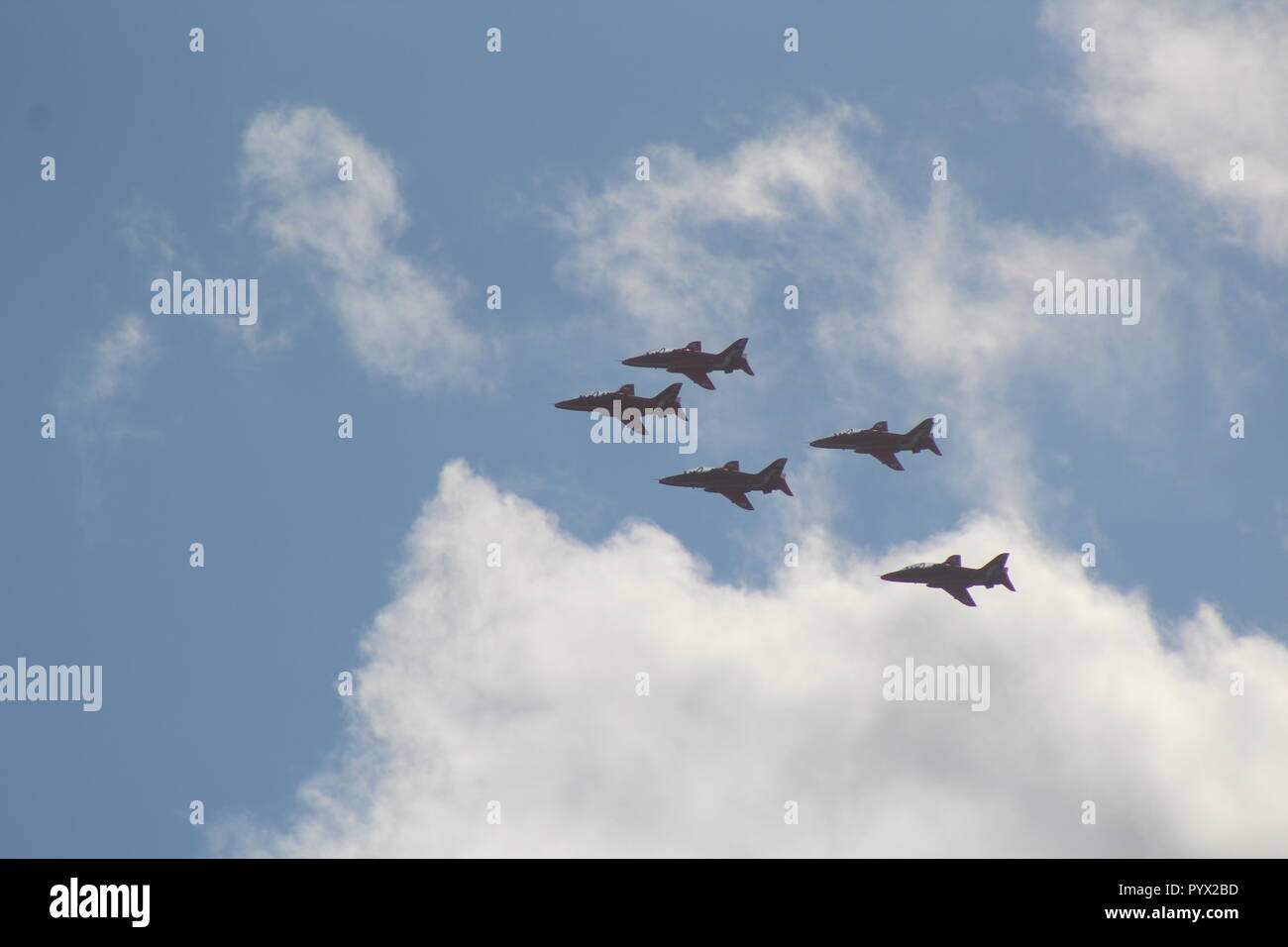 Des flèches rouges volant en formation à travers un ciel bleu avec des nuages Banque D'Images