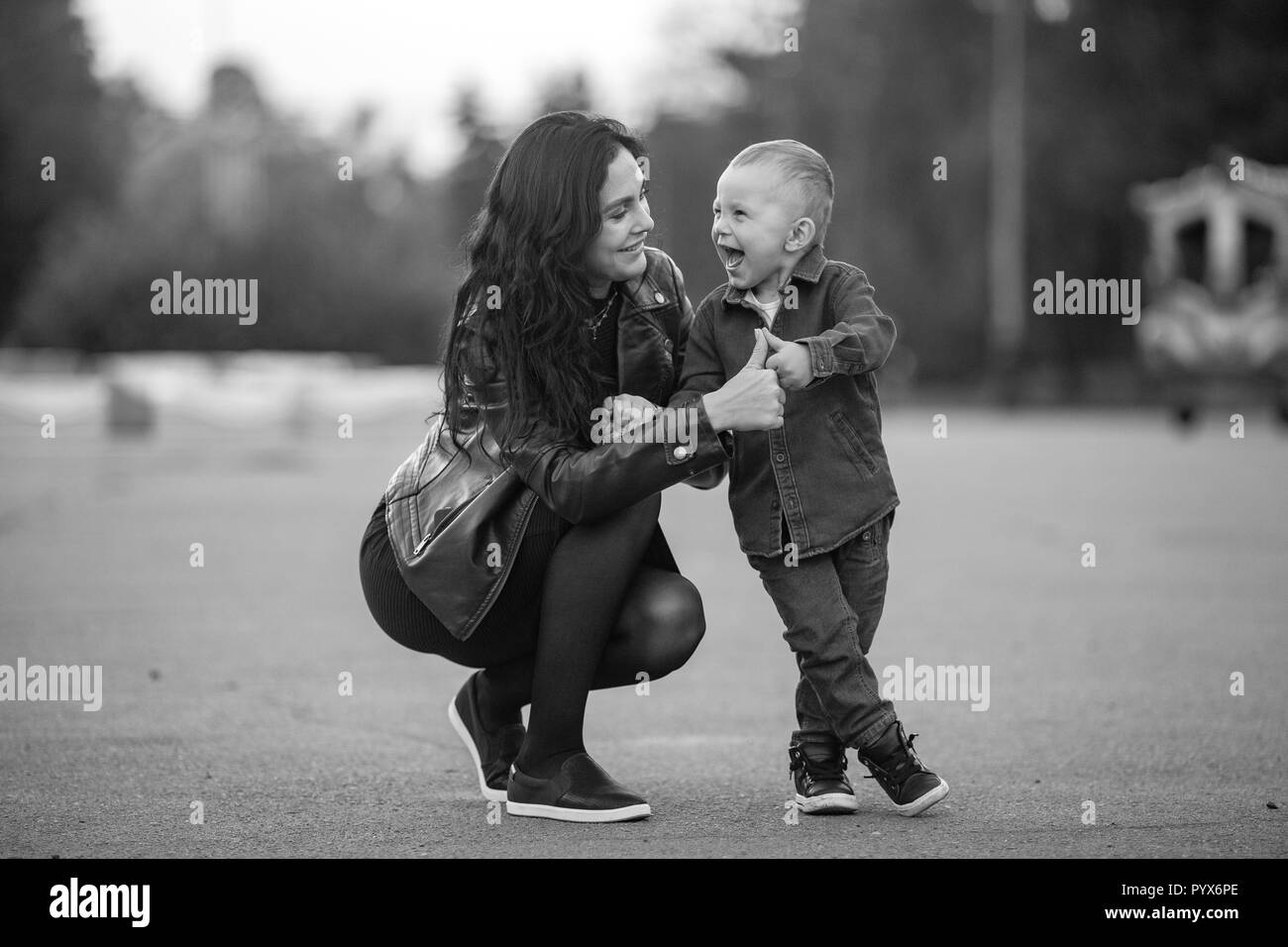 Mère avec son petit fils sont assis et gai rire lors d'une balade dans le parc. Image en noir et blanc. Banque D'Images