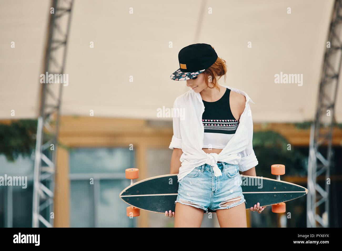 Urban Chic girl posing with Longboard. Hipster girl avec le skate dans la  ville. Sport extrême et d'émotions concept Photo Stock - Alamy