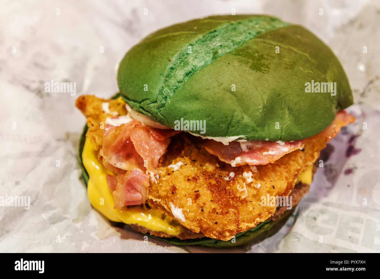 Halloween nightmare burger, comme proposé. Green bun rempli avec du boeuf haché burger, poulet croustillant, bacon, fromage américain et la mayonnaise. Banque D'Images