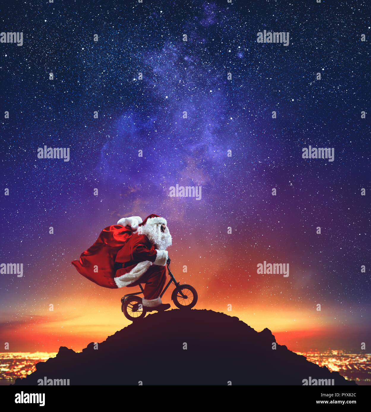 Père Noël sur un petit vélo sur la crête d'une montagne sous les étoiles Banque D'Images
