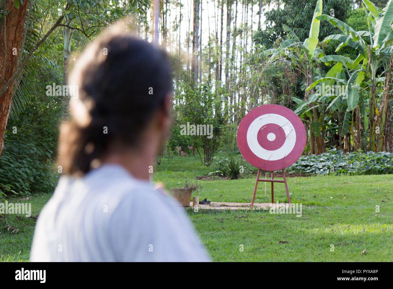 Un sport masculin archer tirant une flèche avec un arc à une cible en bois rouge Banque D'Images