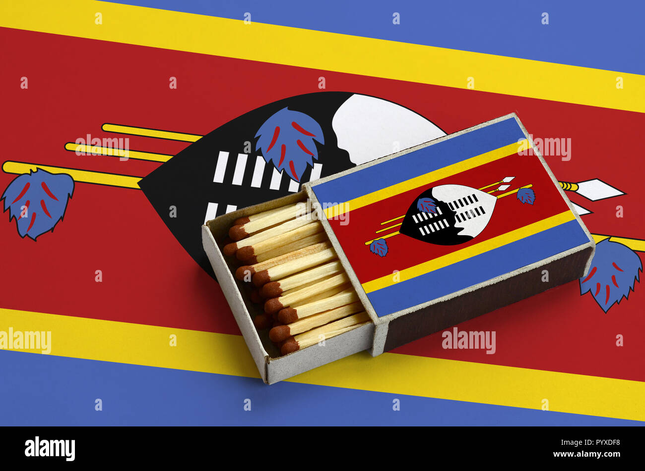 Swaziland drapeau est affiché dans une boîte d'allumettes, qui est rempli avec des allumettes et se trouve sur un grand drapeau. Banque D'Images
