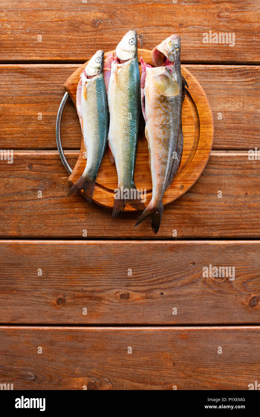 Les prises de poissons frais de la mer se trouve sur une planche à découper sur une table en bois. Top View copy space Banque D'Images