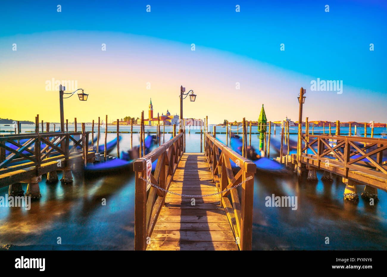 Lagune de Venise au lever du soleil, l'église San Giorgio Maggiore, gondoles et poteaux. L'Italie, l'Europe. Banque D'Images