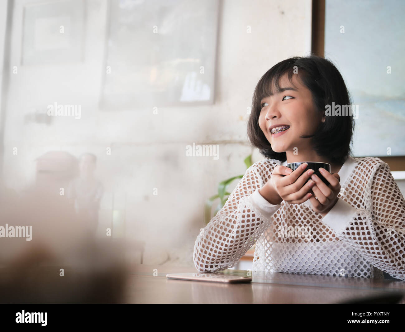 Happy Asian teenager girl holding boisson chaude dans sa main et souriant, style de concept. Banque D'Images