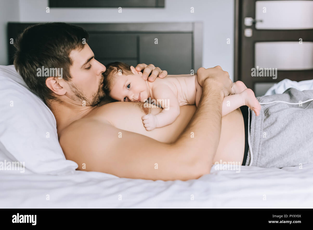 Vue latérale du couple enfant garçon torse nu dans le lit à la maison Photo  Stock - Alamy