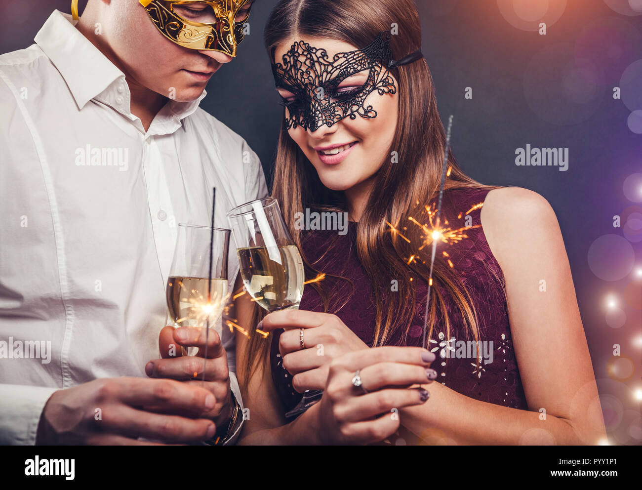 Couples célébrant le Nouvel An de boire du champagne et d'allumer des cierges merveilleux sur la masquerade party Banque D'Images