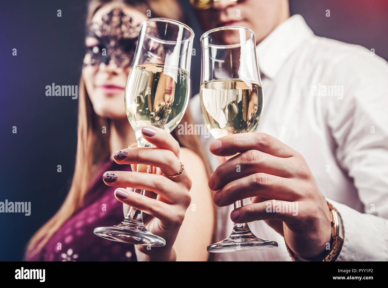 Les jeunes couples célébrant le Nouvel An drinking champagne on masquerade party Banque D'Images