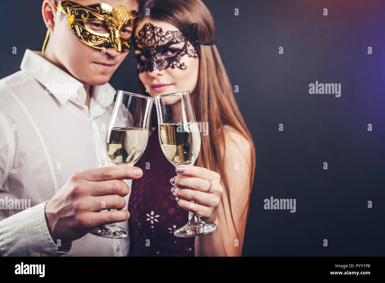 Les jeunes couples célébrant le Nouvel An drinking champagne on masquerade party Banque D'Images