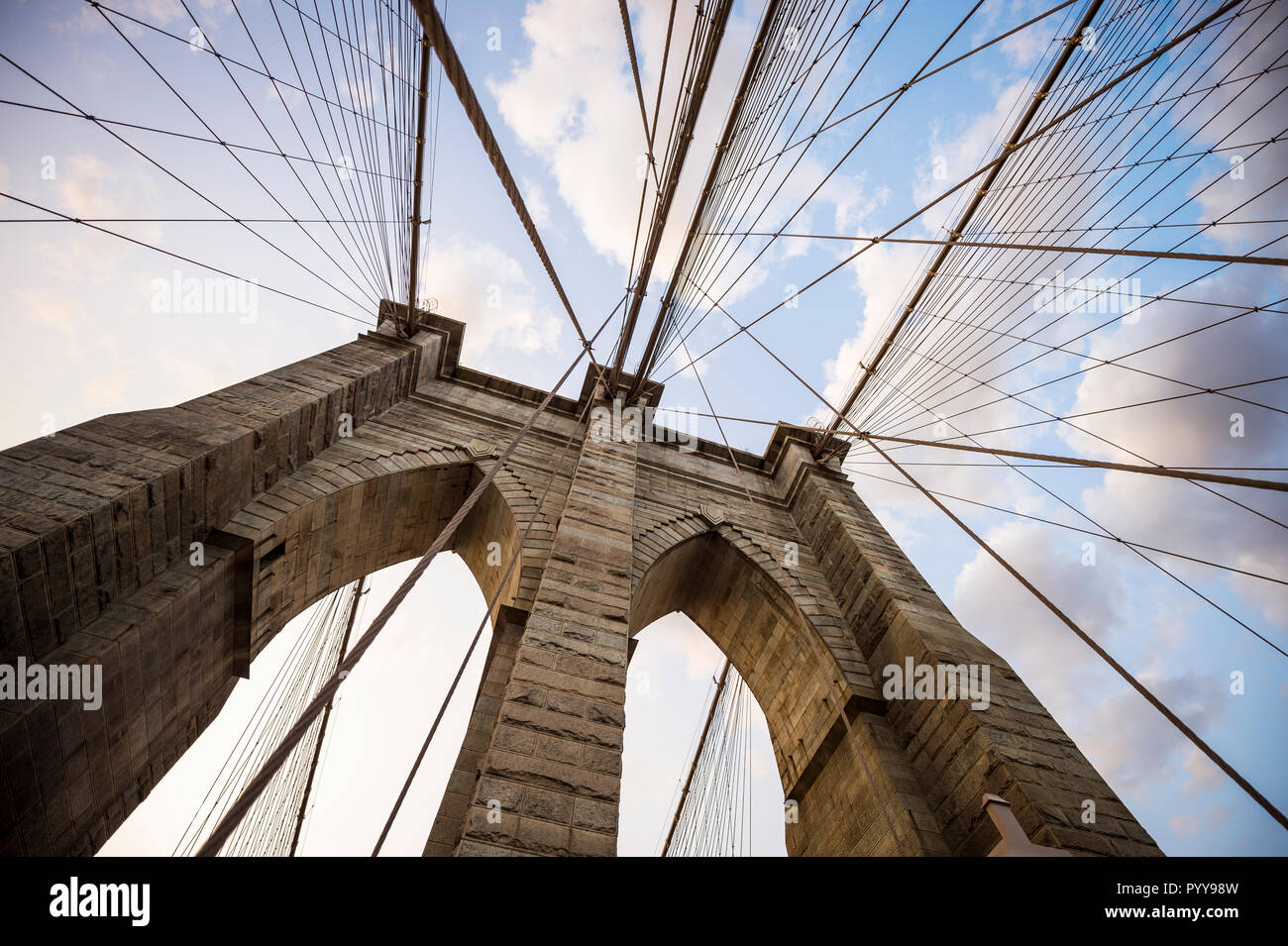 Close-up abstraite de la tour en pierre et de passage de câbles de suspension en acier du pont de Brooklyn sous un ciel coucher de soleil pittoresque Banque D'Images