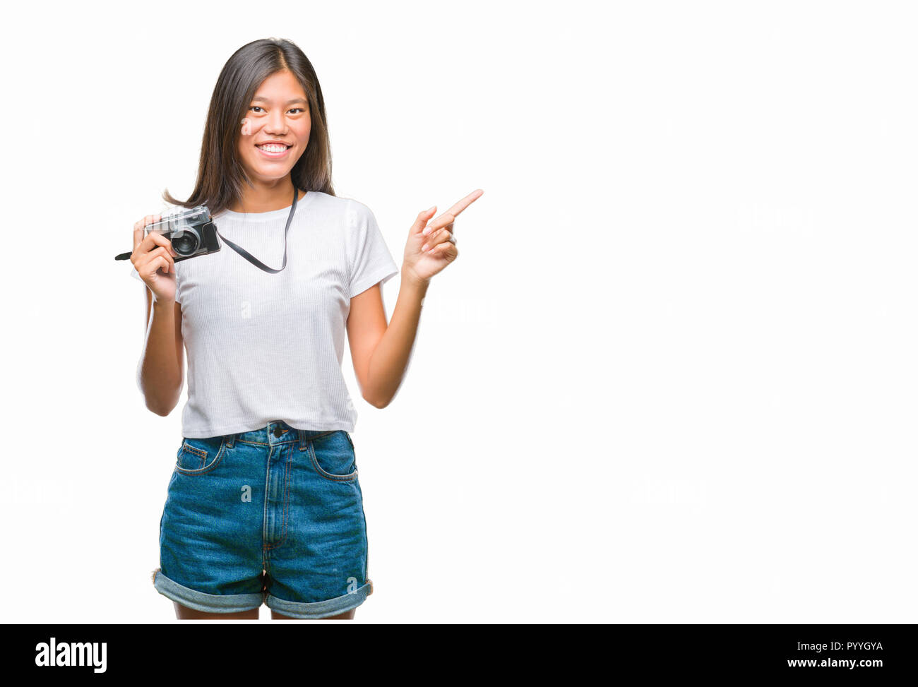 Young Asian woman holding vintagera photo caméra sur fond isolé très heureux avec la main de pointage et le doigt sur le côté Banque D'Images