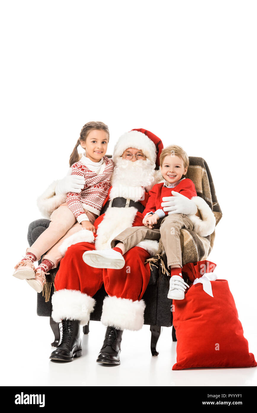 Enfants heureux et santaembracing et looking at camera while sitting in armchair ensemble isolated on white Banque D'Images