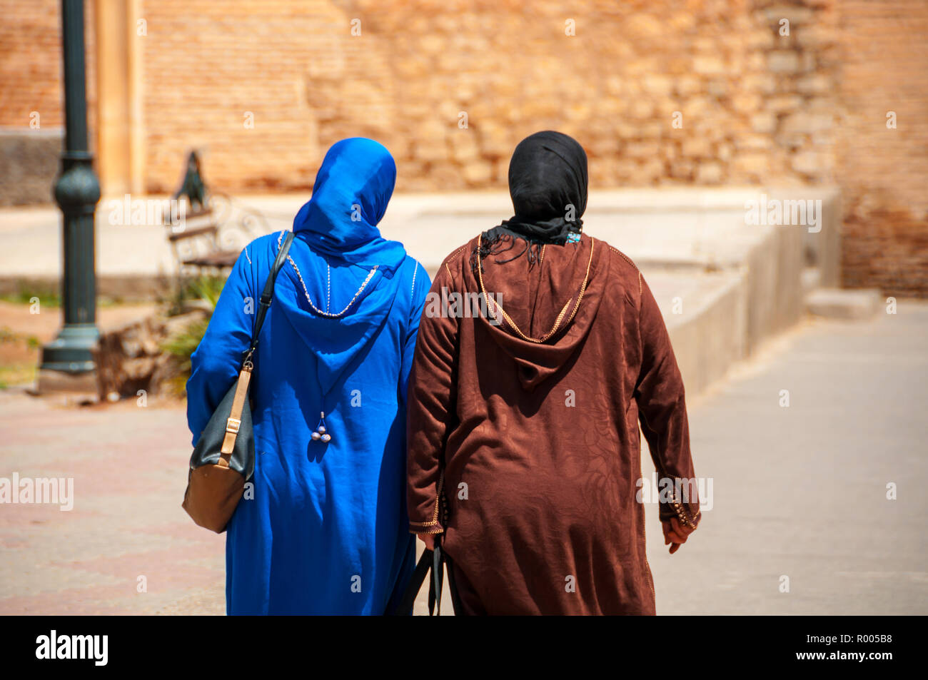 Deux femmes marocaines vu de l'arrière en djellaba bleu et brun se promener dans les rues de la médina de Marrakech, Maroc Banque D'Images