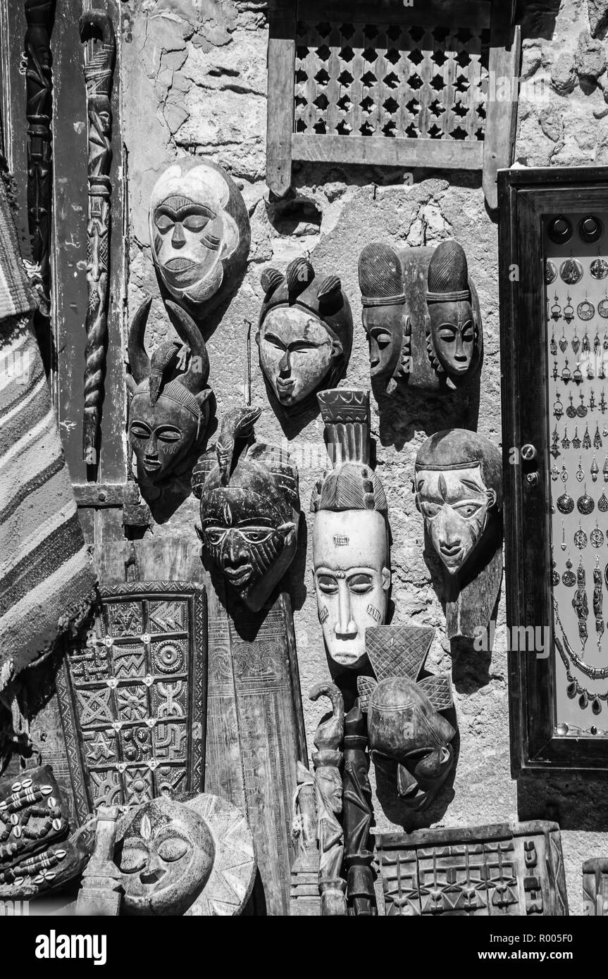 Boutique de souvenirs touristiques au milieu de Médina à Essaouira, Maroc. Les masques en bois élégant sur le mur, d'autres embarcations. Le noir et blanc Banque D'Images