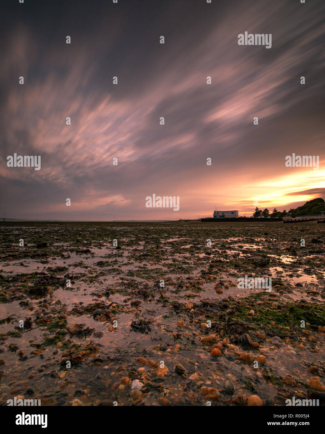 Les nuages de tempête au coucher du soleil sur le rivage à basse ride Banque D'Images