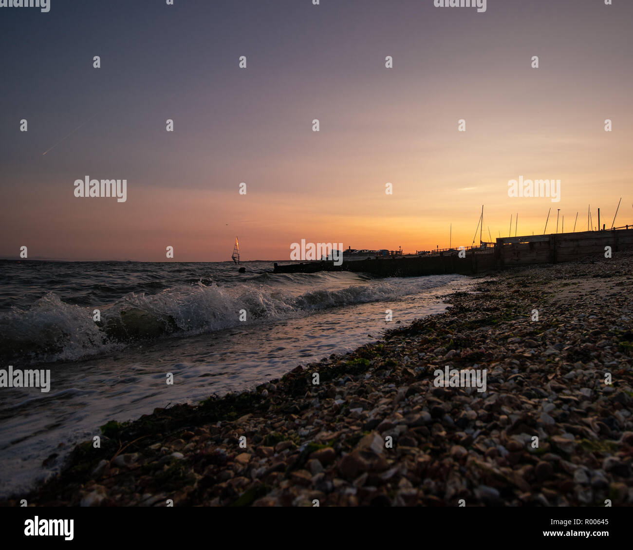 Une plage calme coucher du soleil avec de petites vagues se brisant sur le sable Banque D'Images
