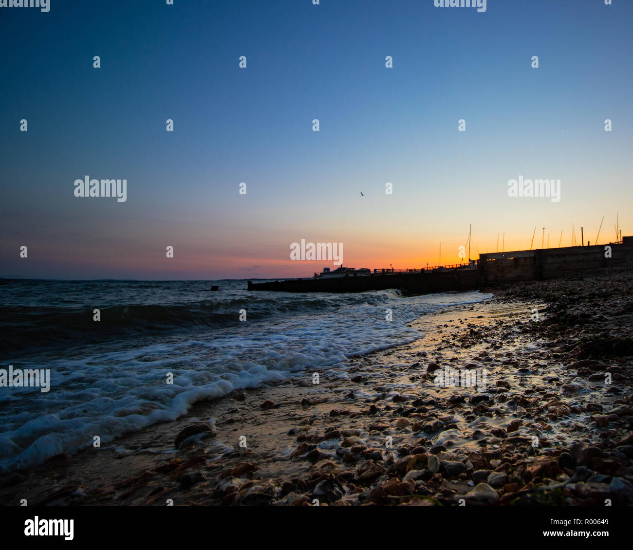 Une plage calme coucher du soleil avec de petites vagues se brisant sur le sable Banque D'Images