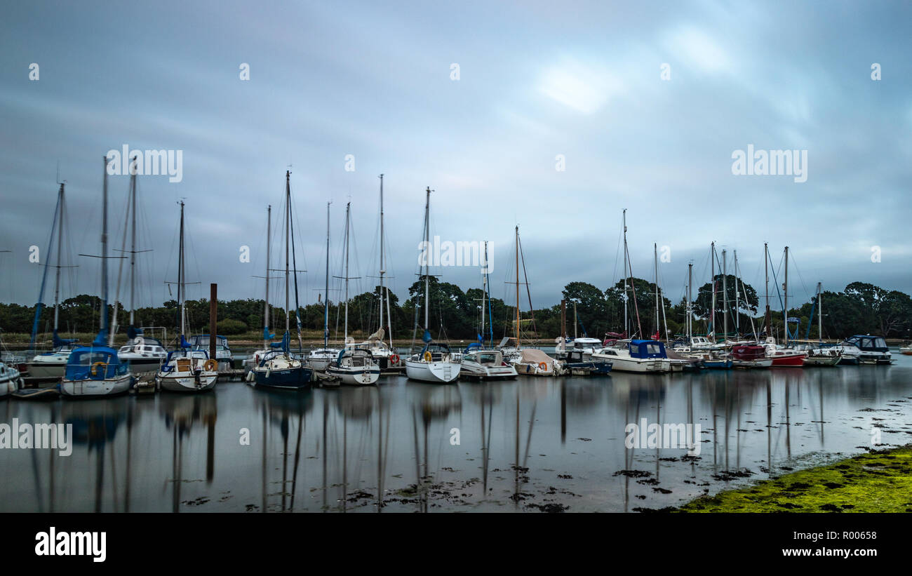 Bateaux à voile alignés dans une marina reflétant sur l'eau Banque D'Images
