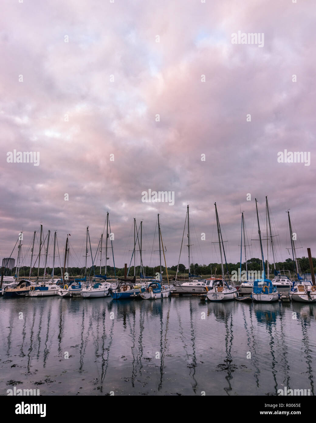 Bateaux à voile alignés dans une marina reflétant sur l'eau Banque D'Images